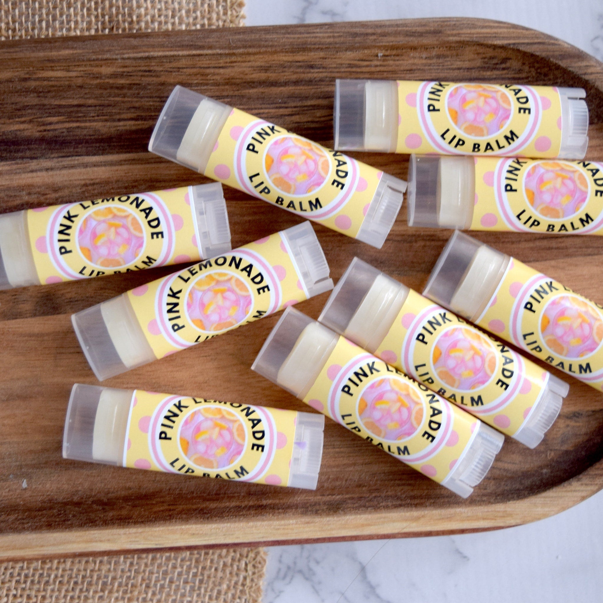 Lip balm tubes with yellow and pink polka dot labels, clear plastic caps, and text reading "Pink Lemonade Lip Balm