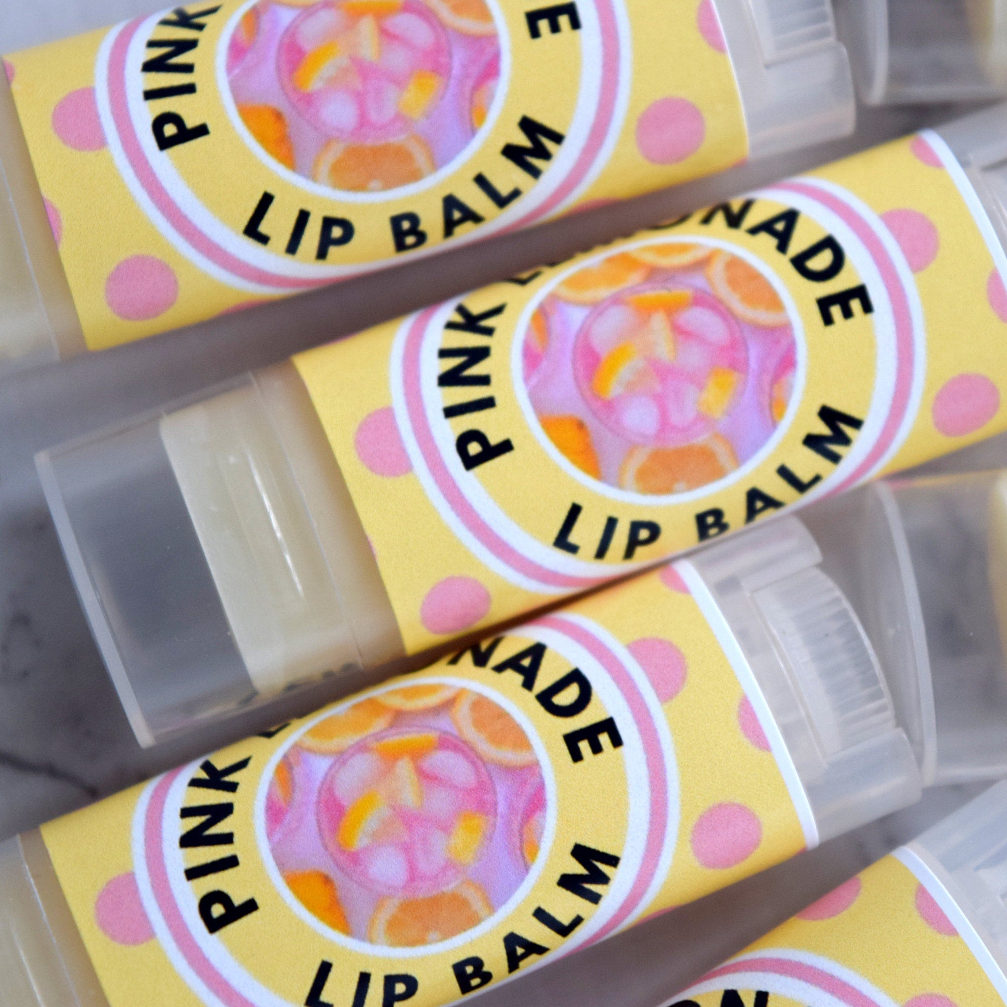 Lip balm tubes with yellow polka dot labels and pink text, "Pink Lemonade" printed on them