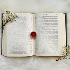 Book pages with white paper and black text, with a small white flower bouquet