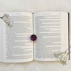 Eye shadow pot with purple, textured, round compact on open book pages