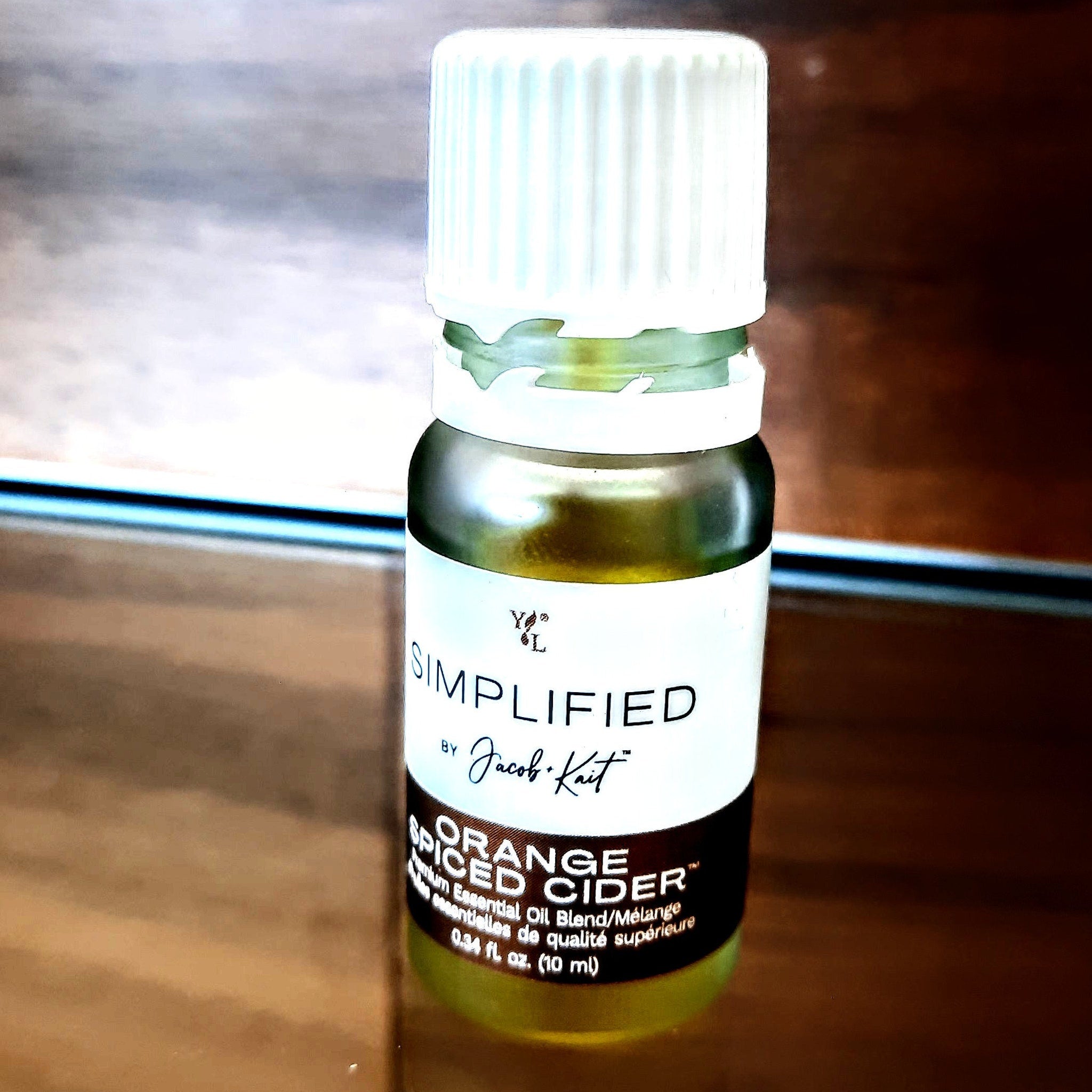 Essential oil bottle with white cap, green liquid, and black label with text "Simplified" and "Orange Spiced Cider