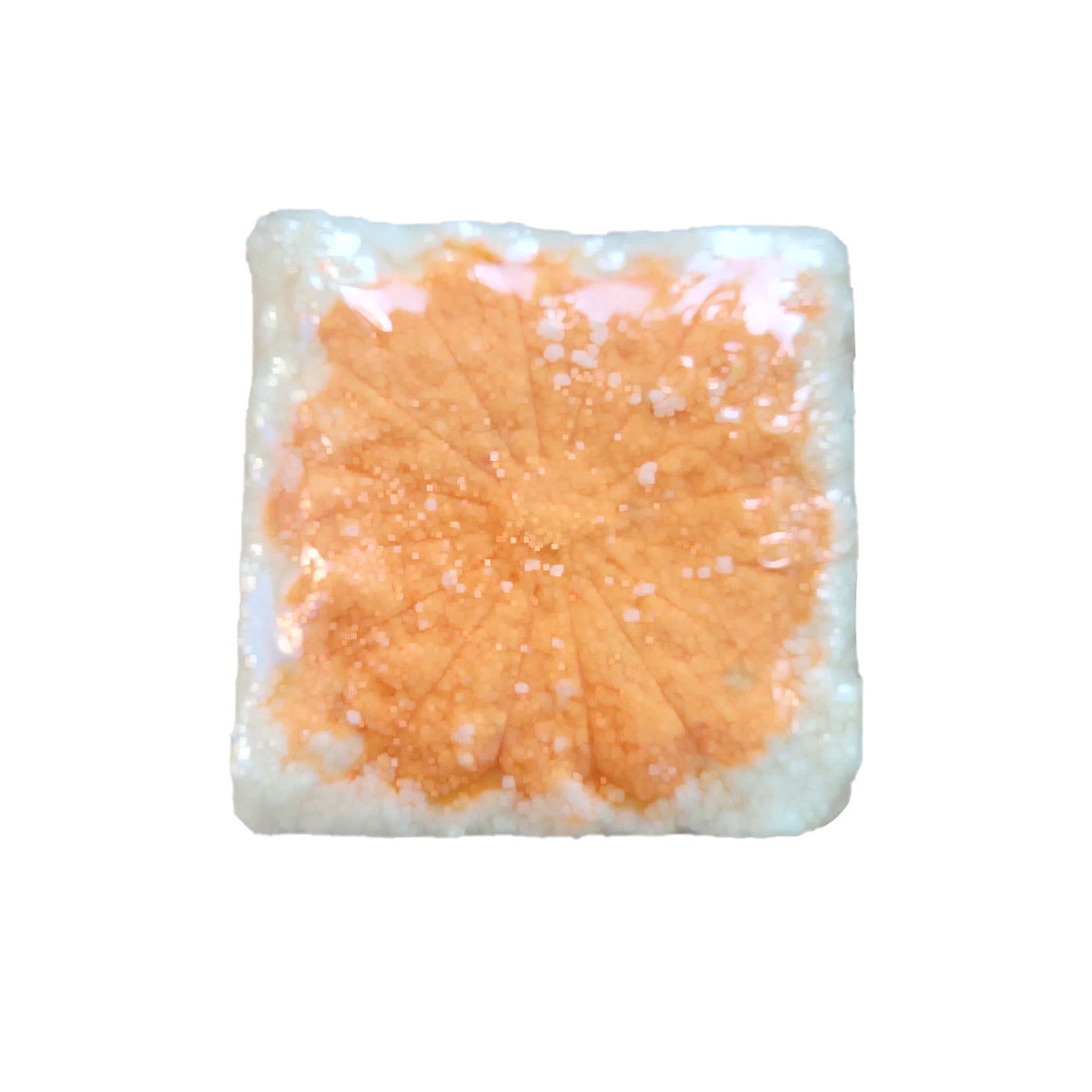 Orange and white square with a leaf pattern, possibly a bath bomb