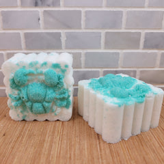Bath bombs with white and teal coloring, textured surface, and a floral design on wood surface