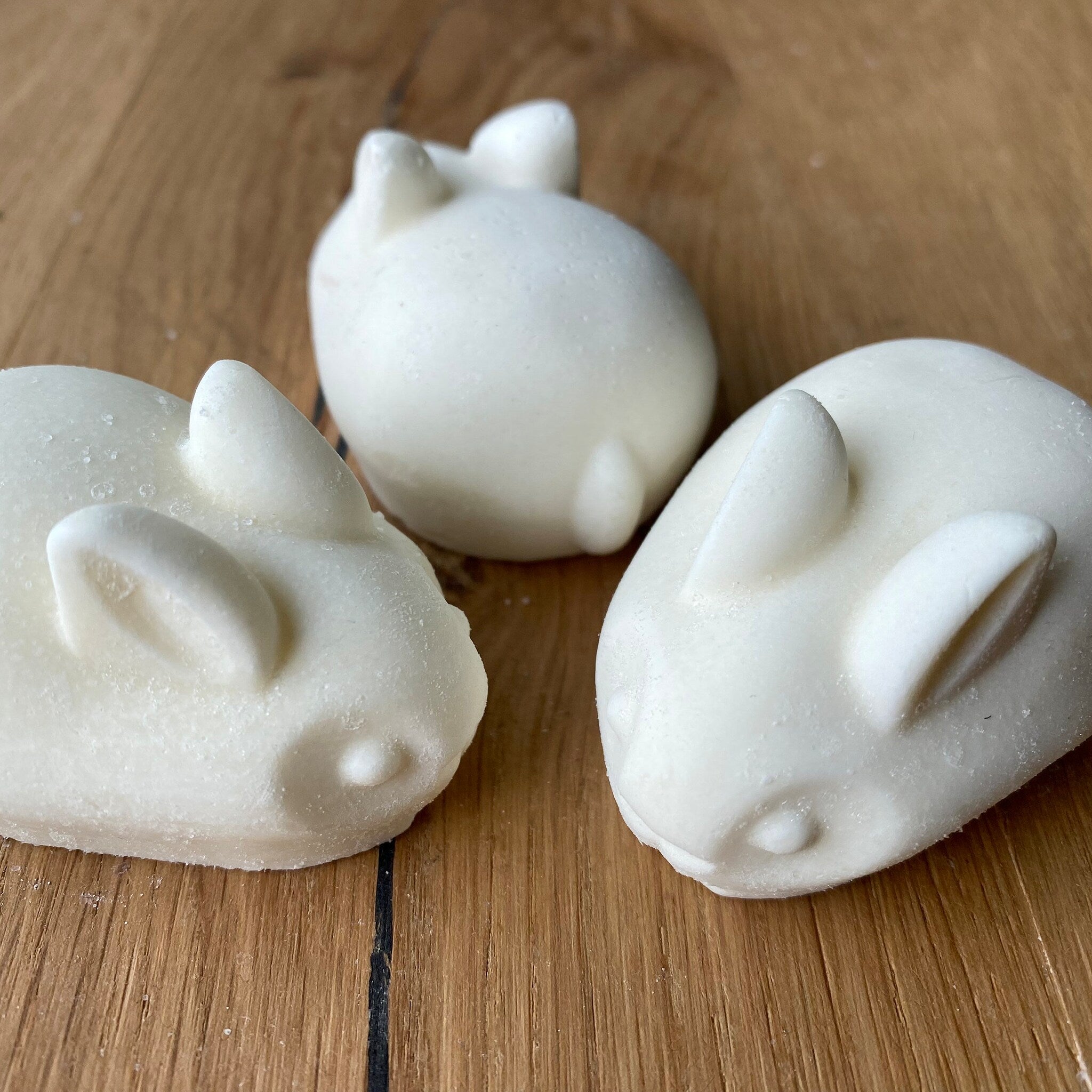 Rabbit shaped soaps, white, textured surface, on a wooden surface