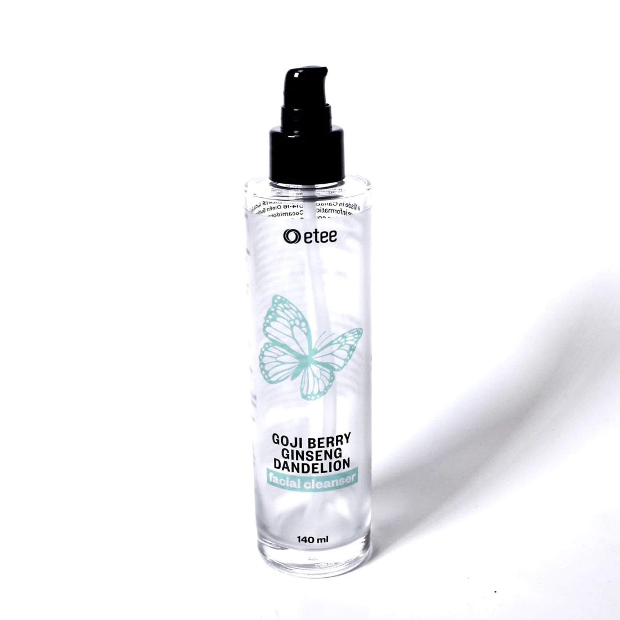 Facial cleanser bottle with black pump, clear glass, and teal butterfly graphic.