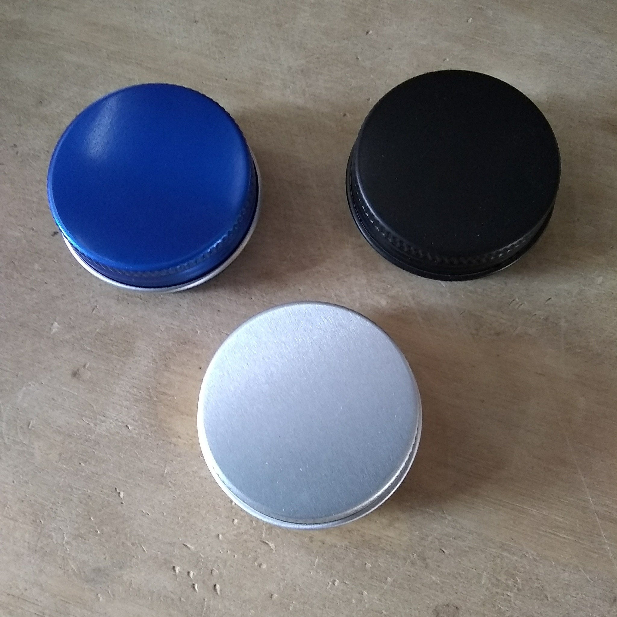Lid caps in blue, black, and silver colors on a wooden surface