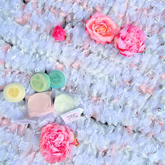 Soap bars in yellow, green, and blue with pink and white floral accents and gift bags