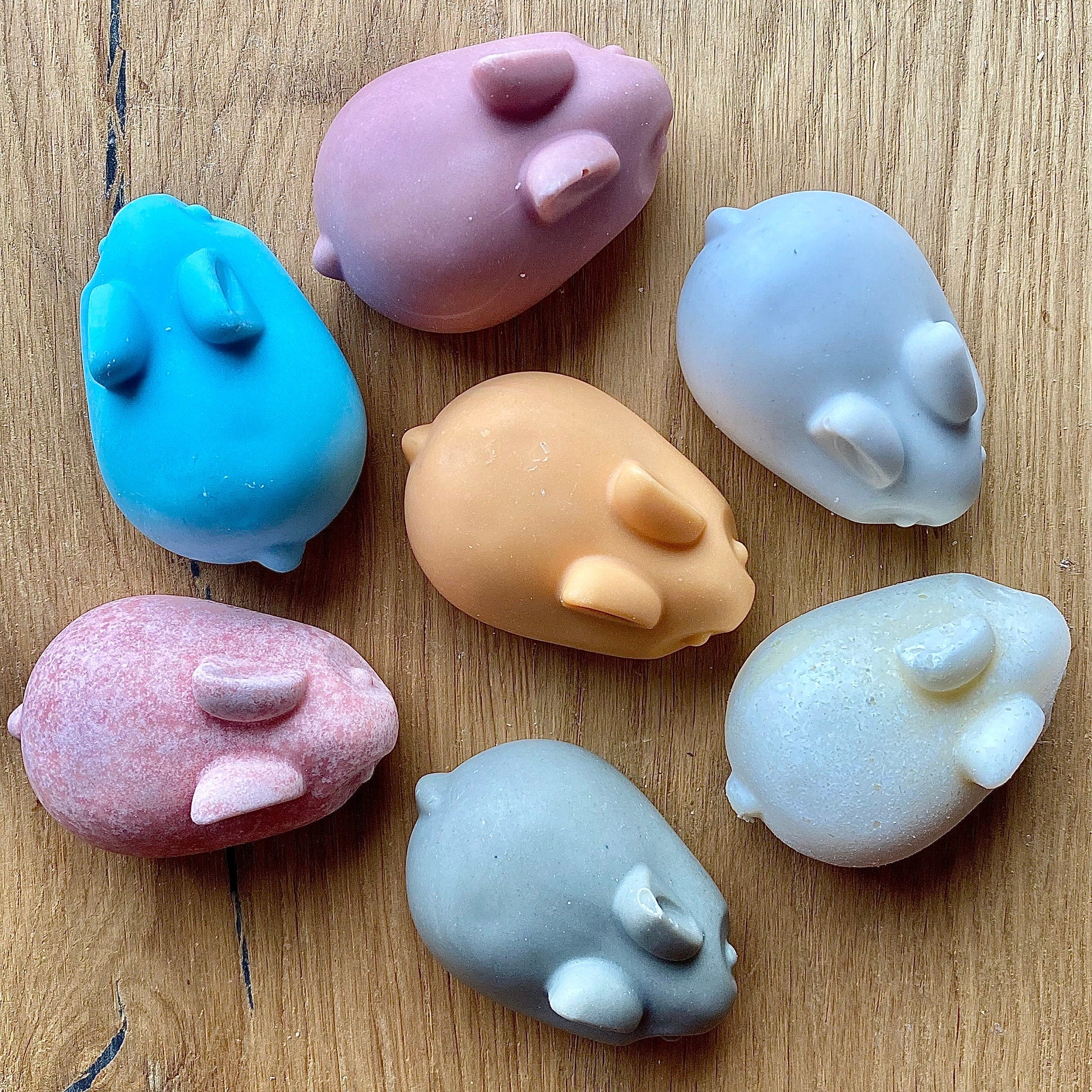 Mouse-shaped soaps in various colors, smooth texture, on a wooden surface