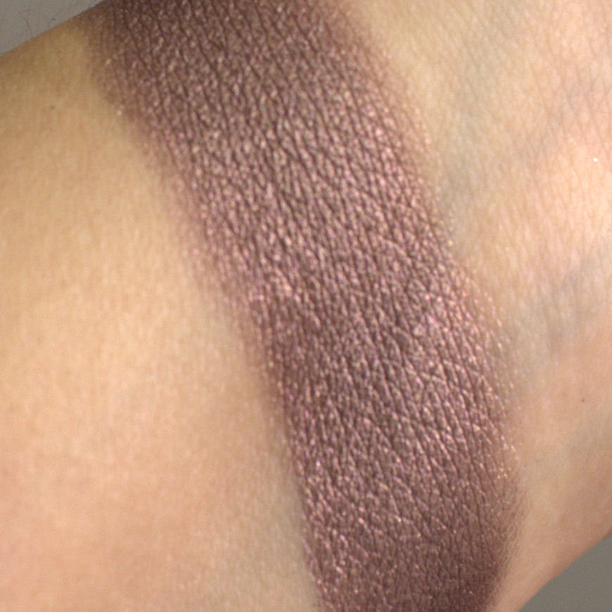 Woman applying shimmering taupe eyeshadow with a blending brush for a soft smoky eye effect