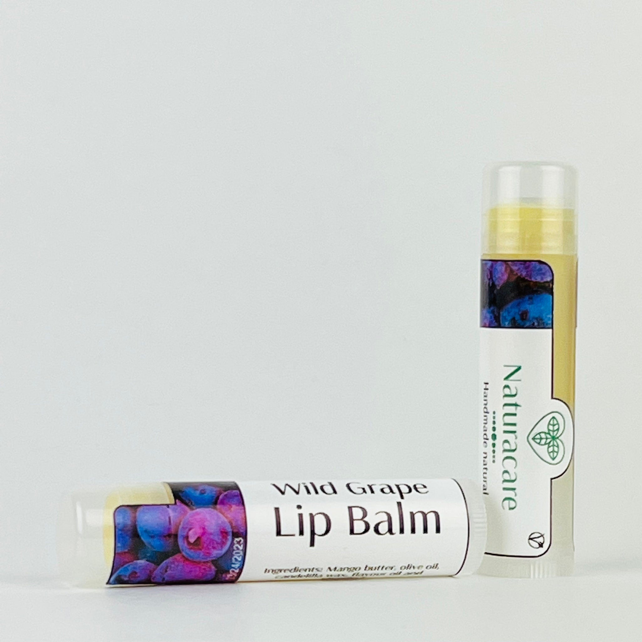 Lip balm tubes with white labels, purple and blue fruit pattern, and Naturacare brand name visible