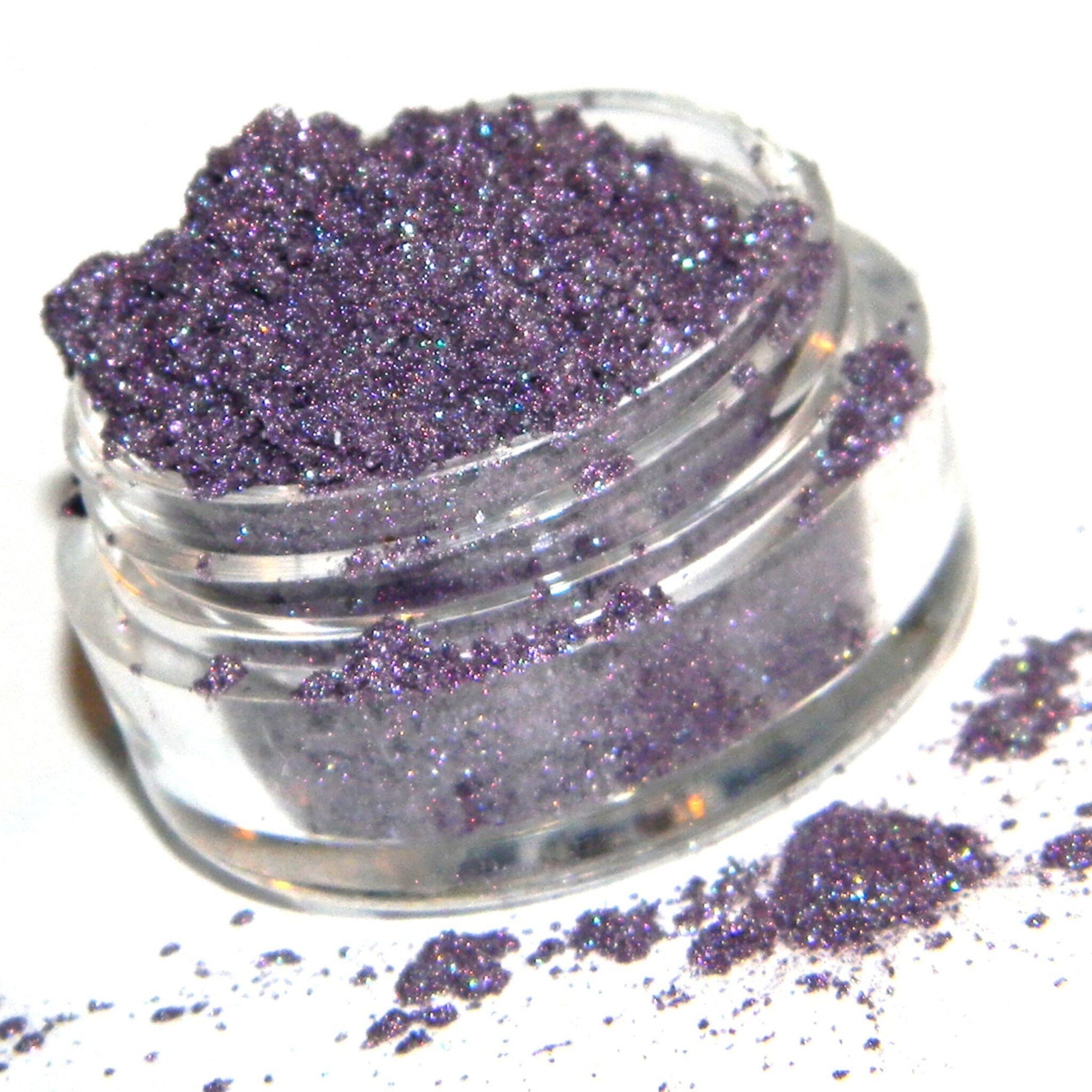 Close-up of shimmery frosty plum purple eyeshadow pan showing metallic sheen and smooth texture