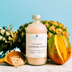 Cleansing Grains bottle with white label, light brown liquid, and Blue Haven Holistics branding next to fruit
