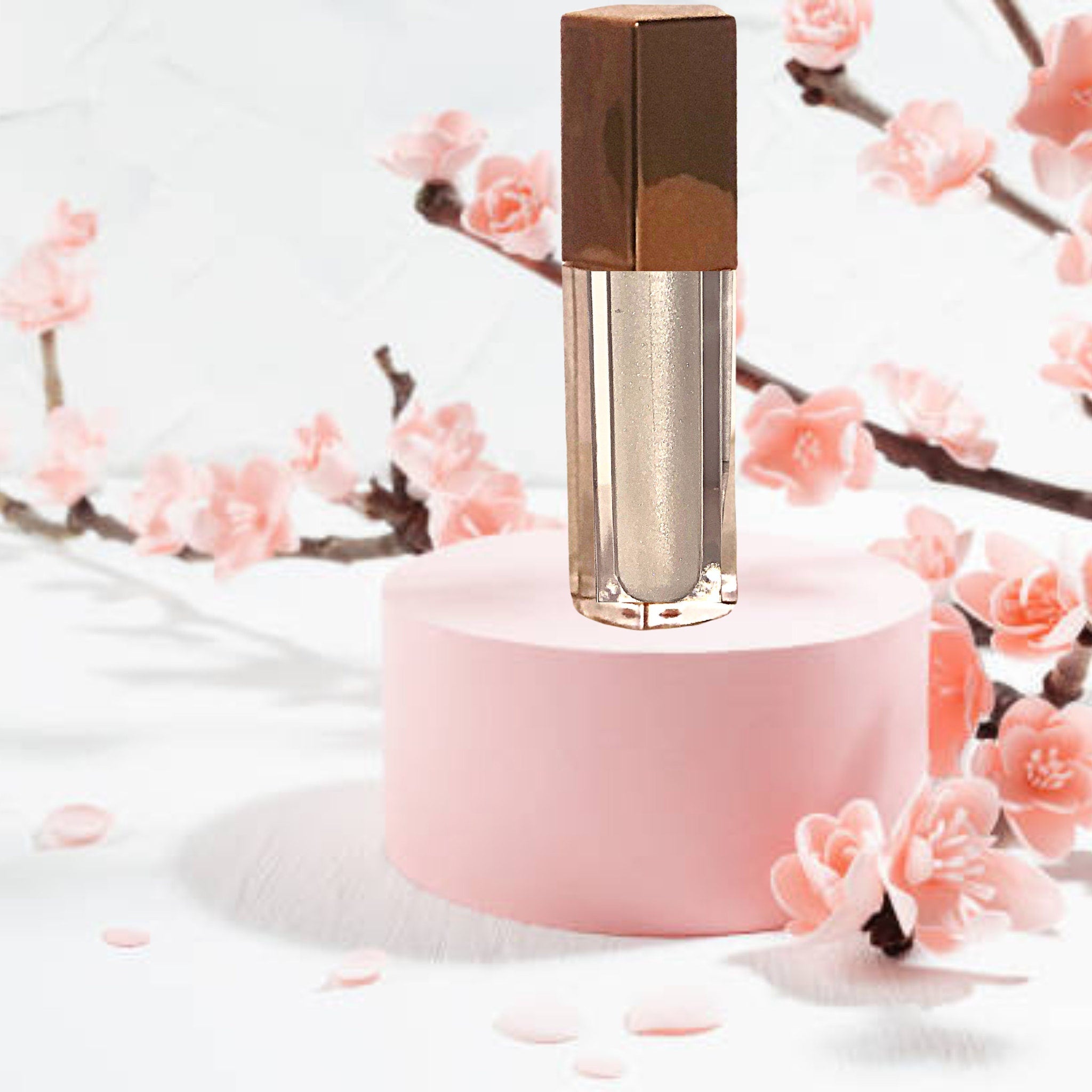 Lip gloss with gold cap, clear tube, and silver shimmer, on pink display
