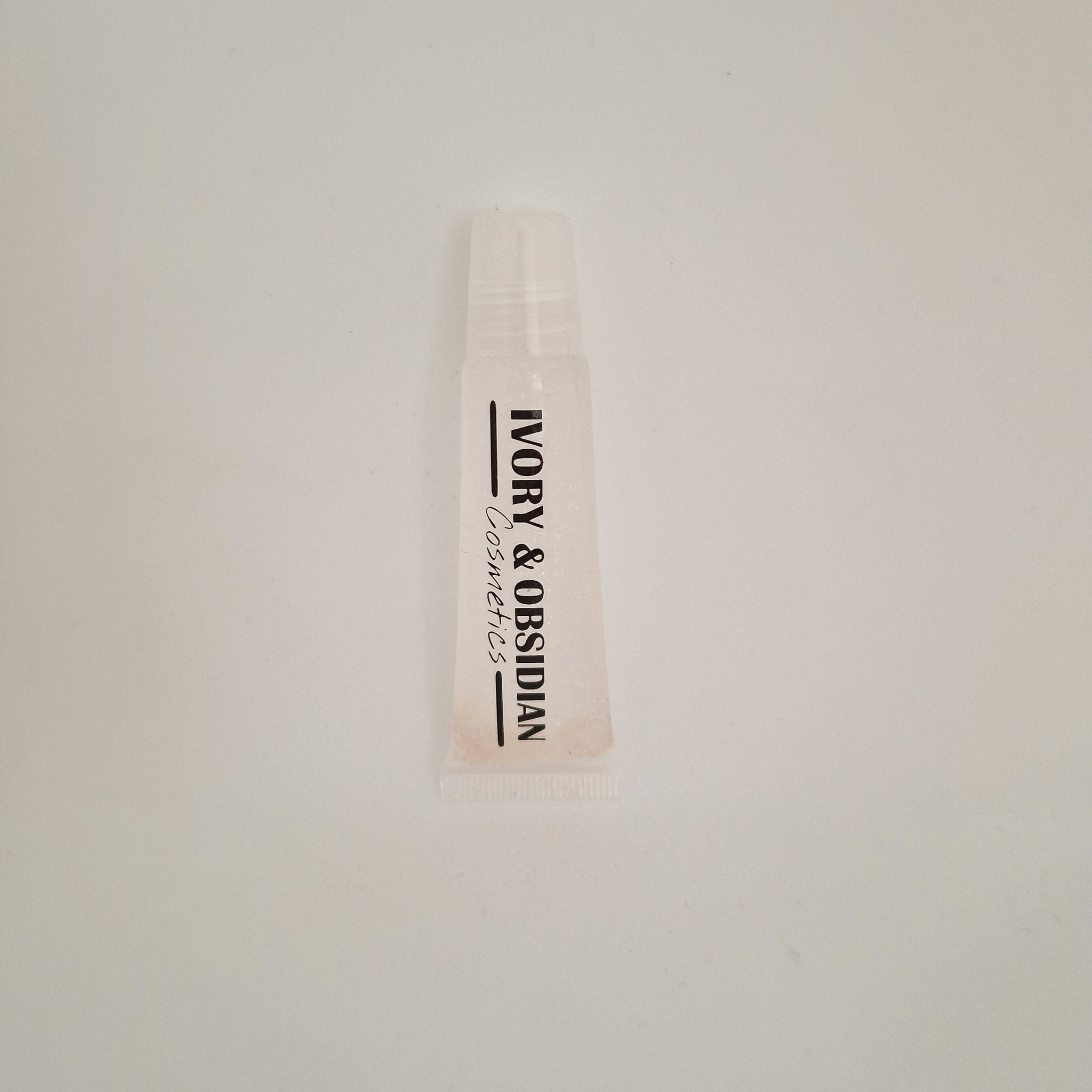 Lip gloss tube, clear plastic with Ivory & Obsidian Cosmetics text, light pink tint