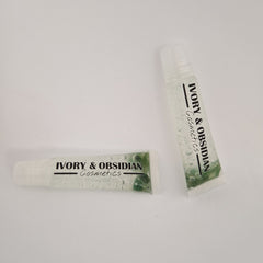 Lip gloss tubes with clear liquid, green beads, and "IVORY & OBSIDIAN Cosmetics" text on white background