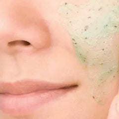 Facial Cleanser with green and black scrub applied to face, close-up view