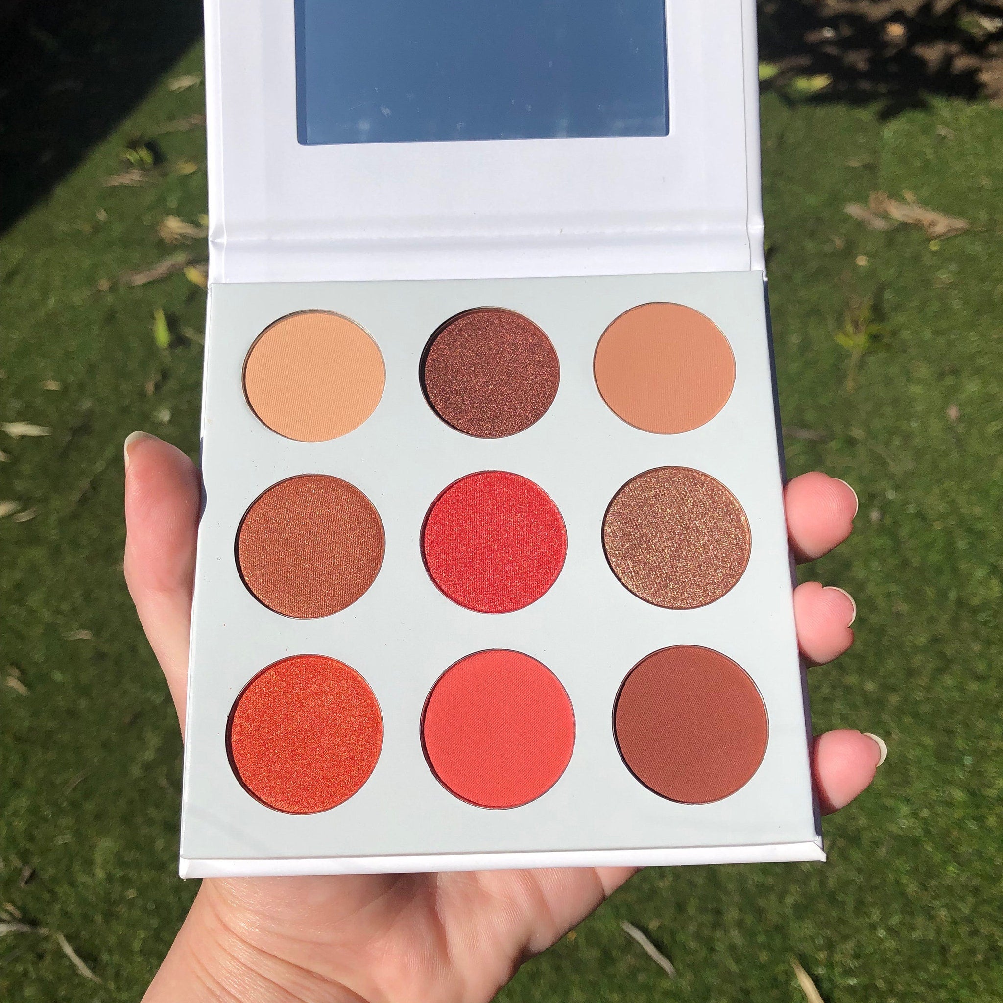Close-up of the Red Daisies Eye Shadow Palette showing vibrant matte red and shimmer pink shades with floral imprint.