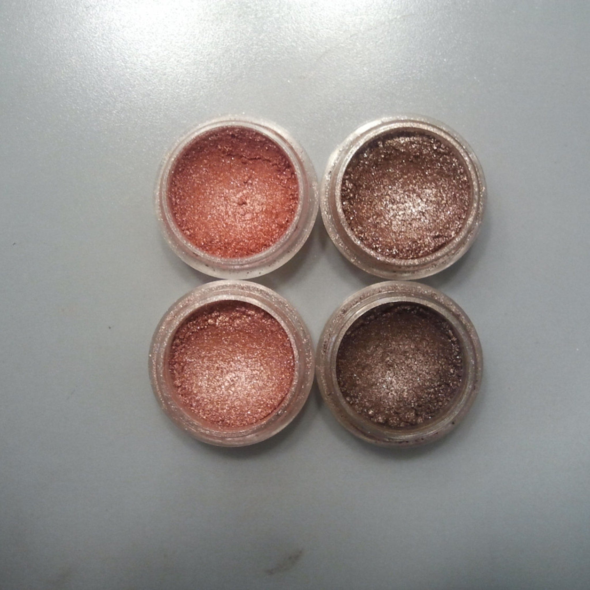 Close-up of shimmering pink and bronze eye shadow palette with embossed floral design on compact