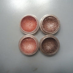 Close-up of shimmering pink and bronze eye shadow palette with embossed floral design on compact