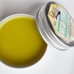 Lip balm in a silver tin, with yellow balm, and Desert Rose label visible.