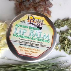 Lip balm tin with Desert Rose label, silver metal, surrounded by herbs