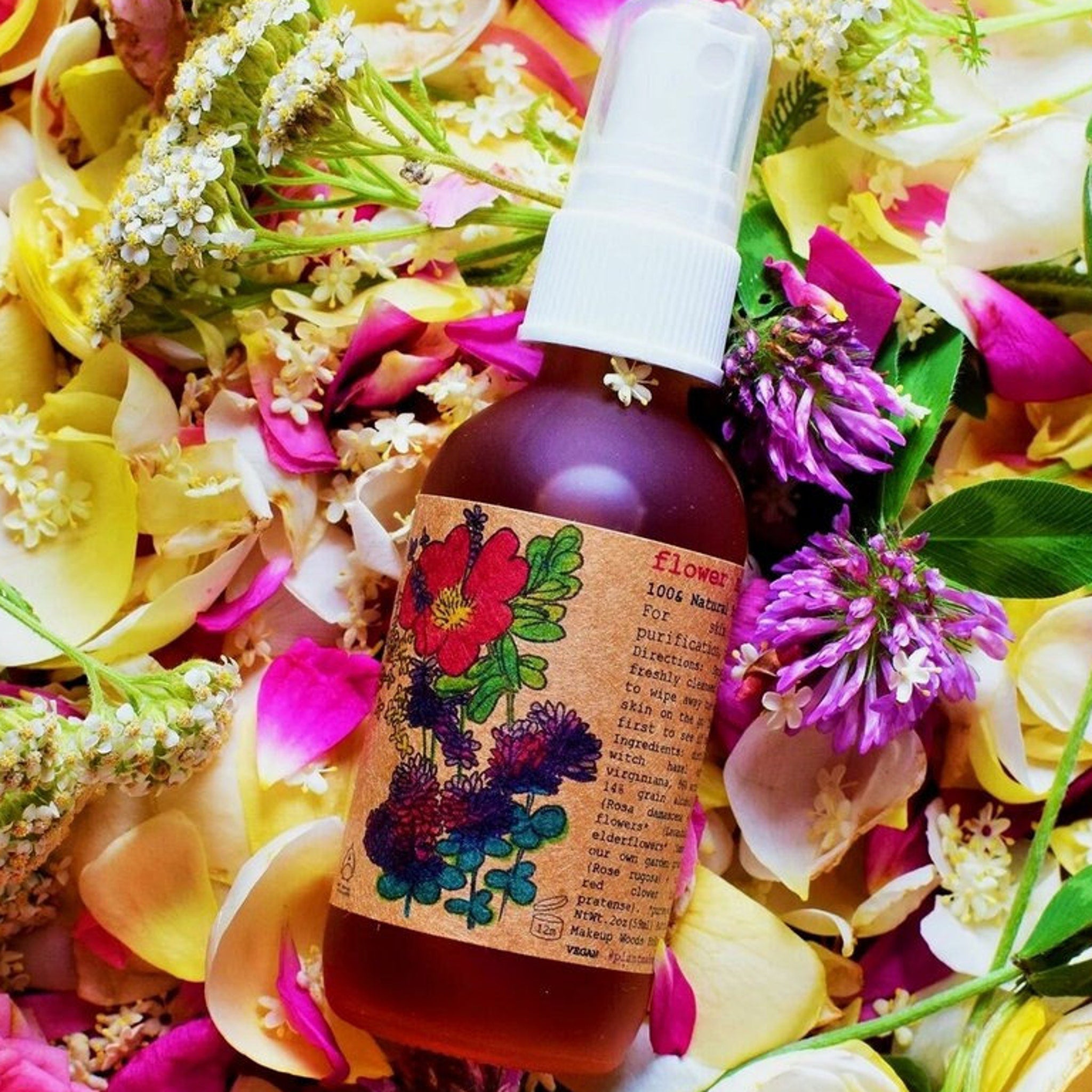 Toner bottle with floral label, clear spray top, and surrounded by colorful petals and flowers