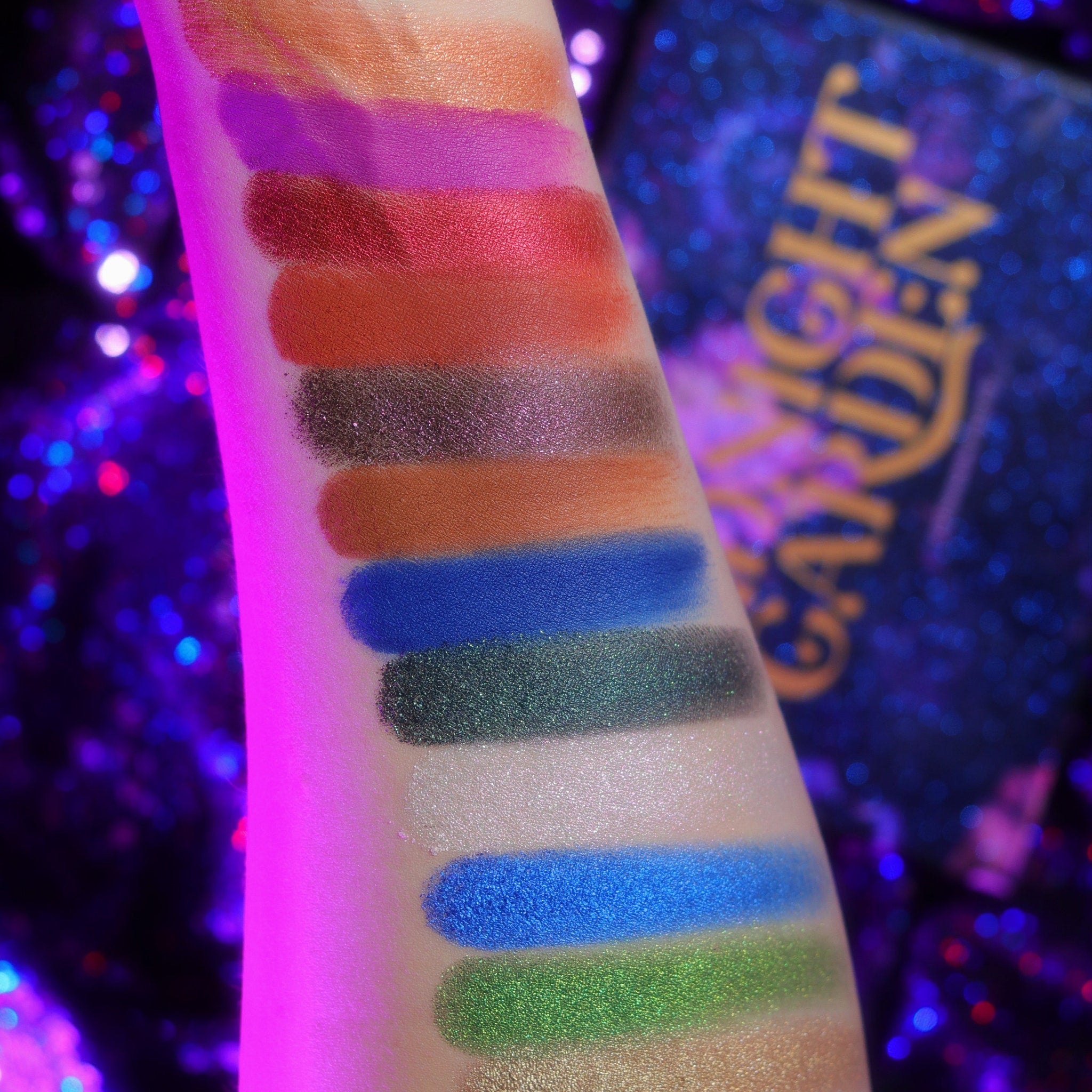 Close-up of shimmering teal and plum eyeshadows in the Midnight Garden palette with floral embossed design