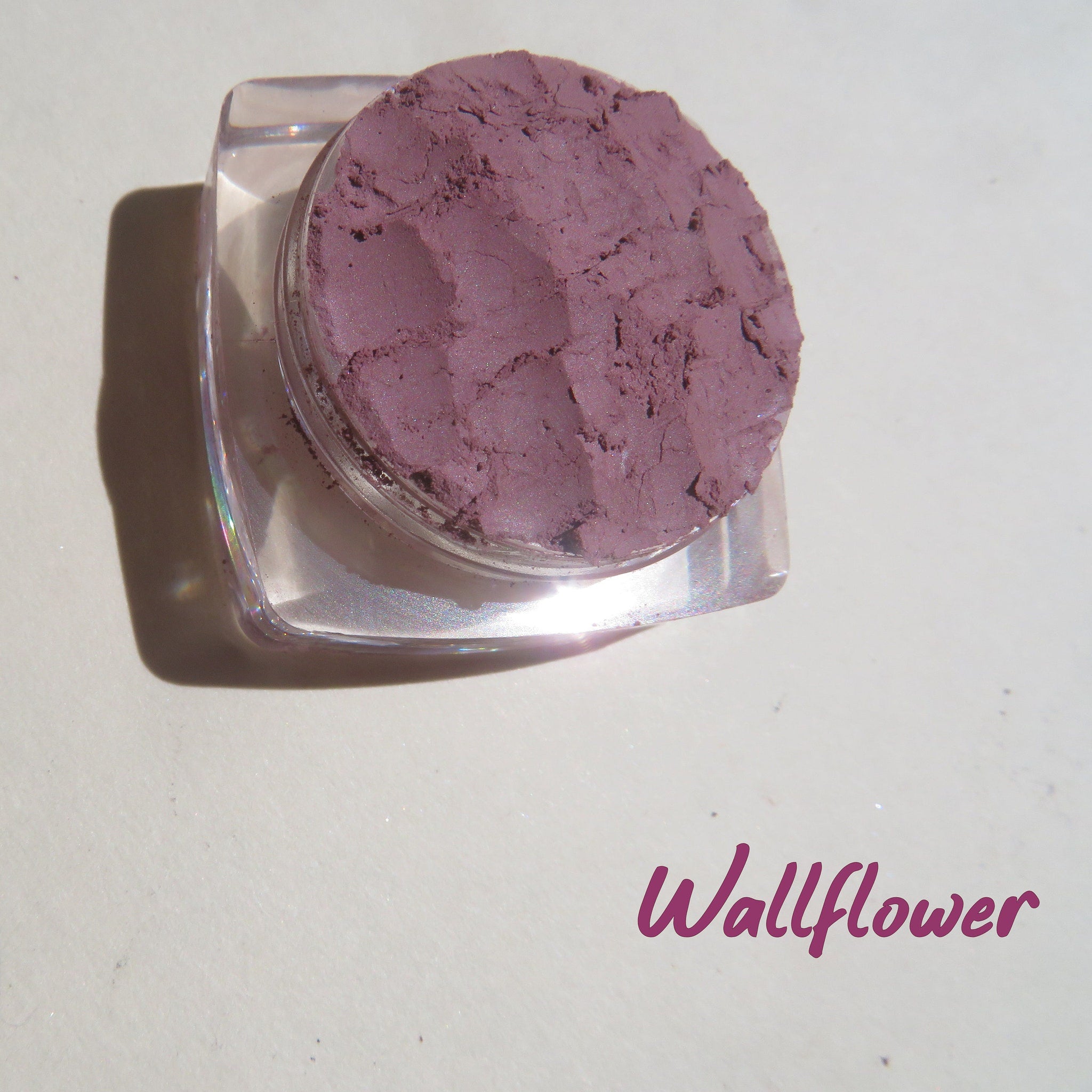 Side view of matte purple mineral eyeshadow in loose pigment form, showcasing texture and depth