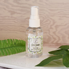 Facial toner bottle, clear plastic, white cap, "Cute Cumber" label, on a tray
