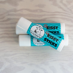 Lip balm tubes, white and teal, with "Kissy Sticks" text and Goat Fetching Soap logo on each tube
