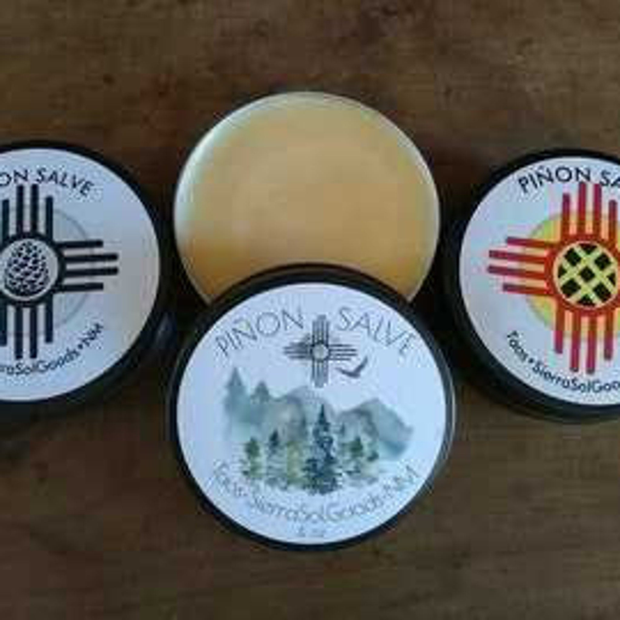 Salves in black tins with white labels, yellow salve in center, Pion Sap brand visible