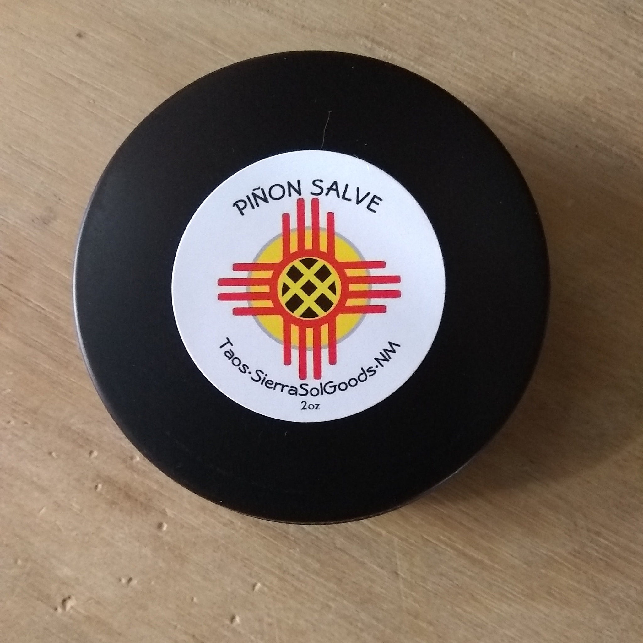Piñon salve in black container with white label and red and yellow design, Pion Sap brand