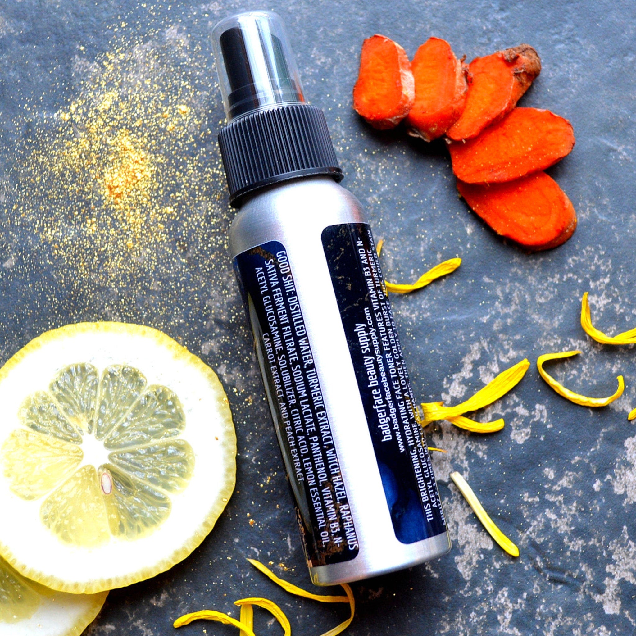 Toner spray bottle with silver metal, black cap, and Badgerface Beauty Supply label, with turmeric and lemon slices