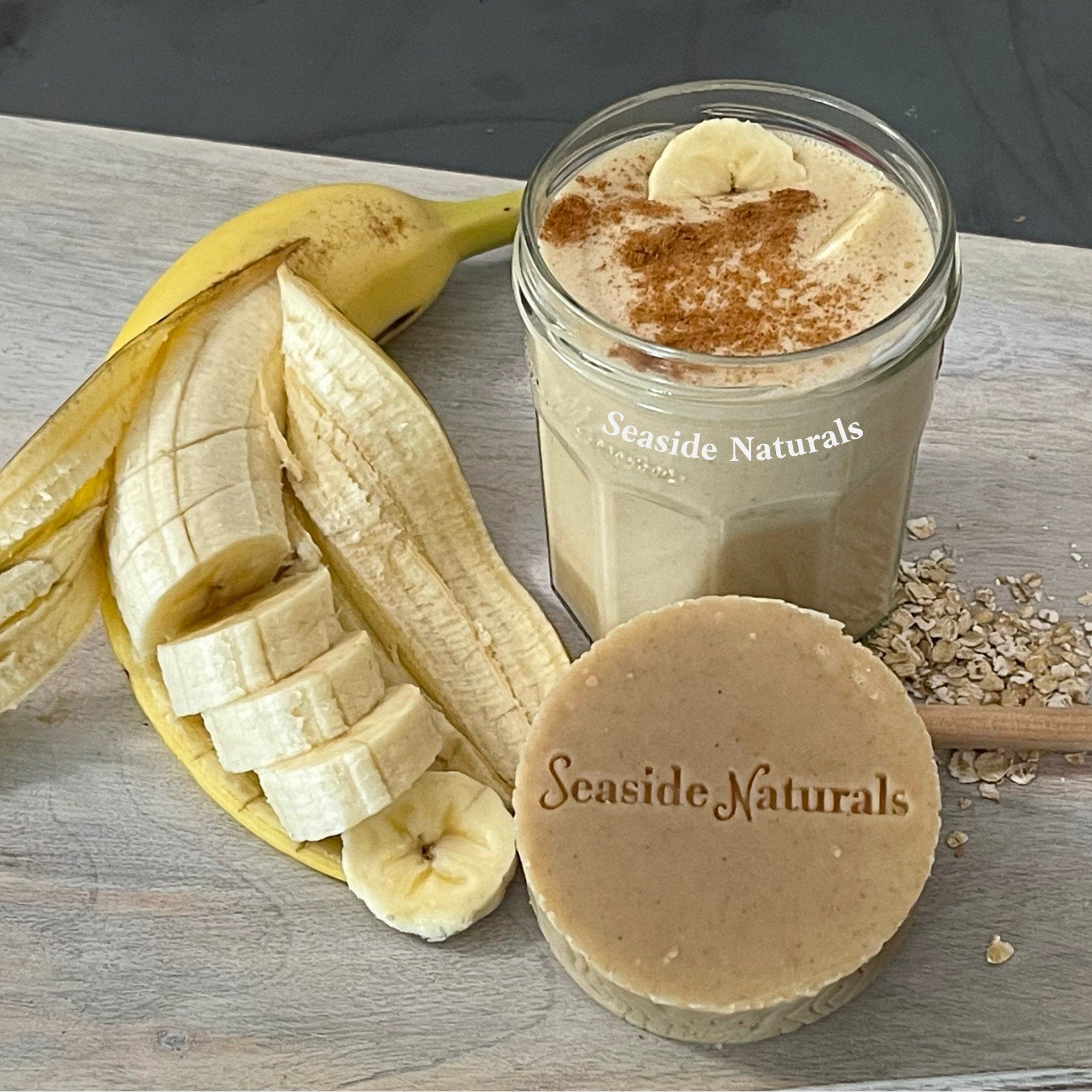 Banana slices with peeled yellow skin, smoothie in glass, and Seaside Naturals soap on wood surface