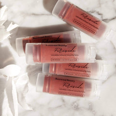 Lip balm tubes with red tint, clear plastic, and Basswood Beauty Fireside branding