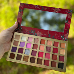 Close-up of fingertips applying deep red Pigmented Bad Blood Eyeshadow to eyelid with smooth blending