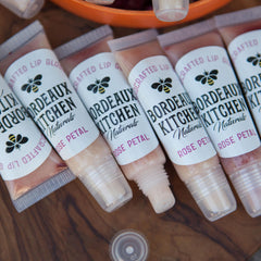 Lip gloss tubes with clear plastic, pink liquid, and white labels with "Bordeaux Kitchen" text