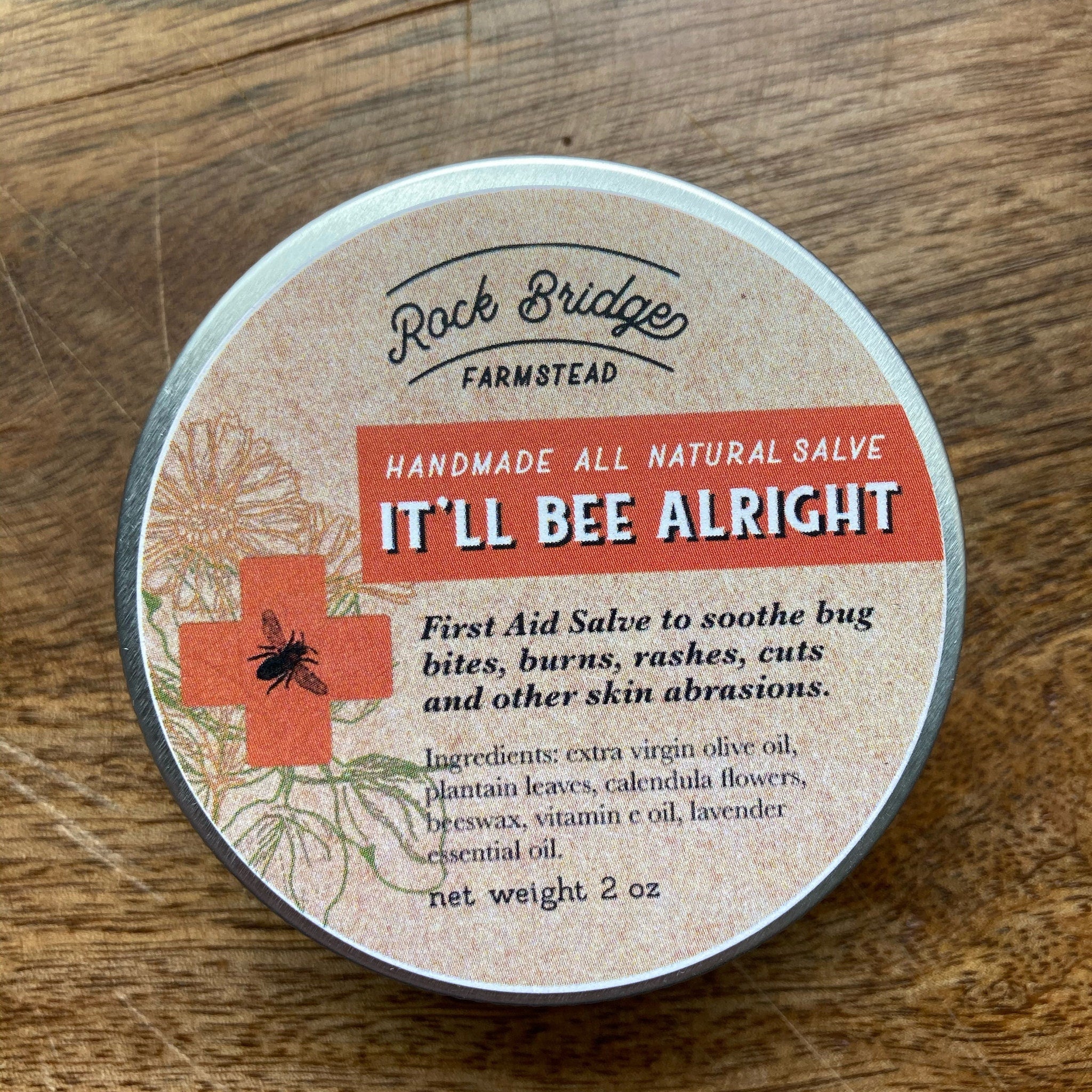 Salve tin with orange and tan label, Rock Bridge Farmstead brand, for skin abrasions