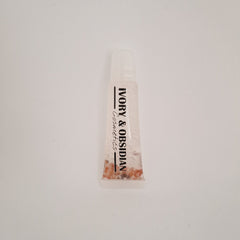 Lip gloss tube with clear liquid, Ivory & Obsidian branding, and small beads inside