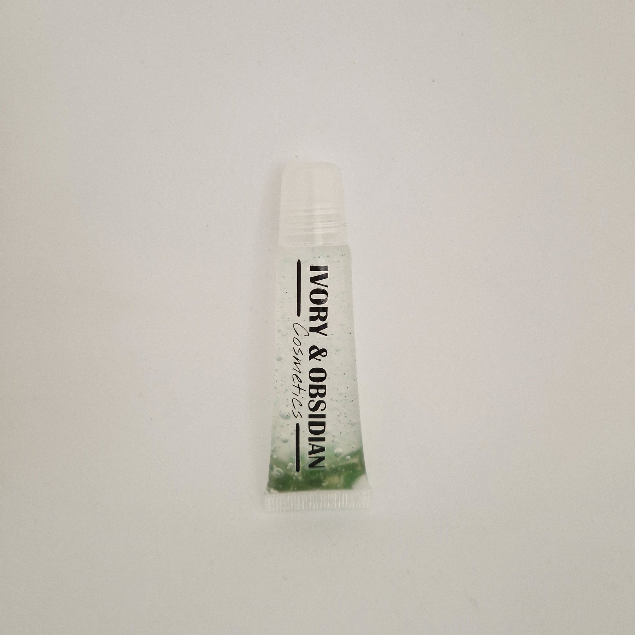 Lip gloss tube with clear liquid, green base, and Ivory & Obsidian Cosmetics text