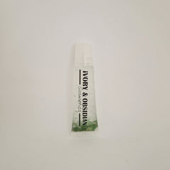 Lip gloss tube with clear liquid, green base, and Ivory & Obsidian Cosmetics text
