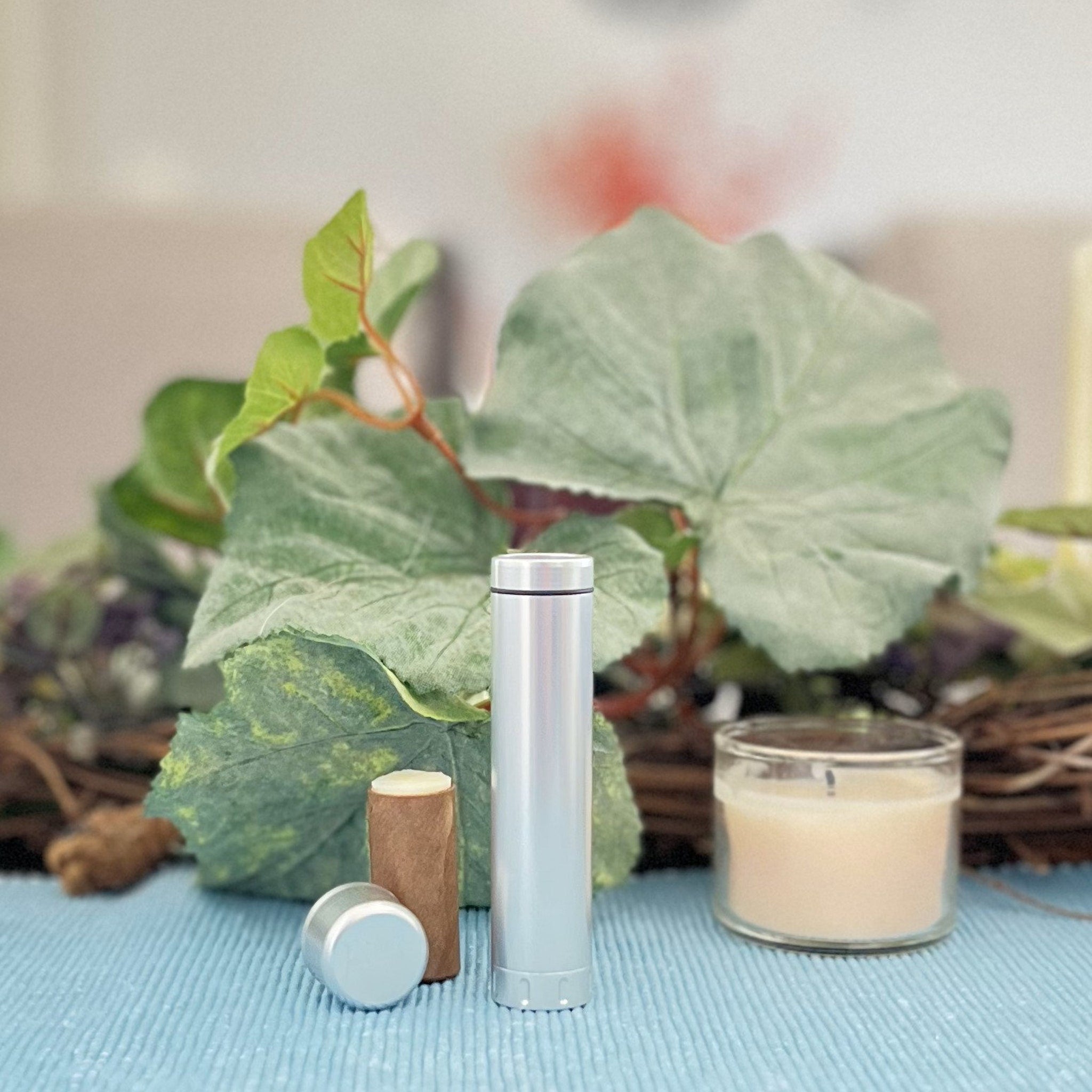 Silver cylindrical container with silver cap and brown cylindrical object on blue textured surface