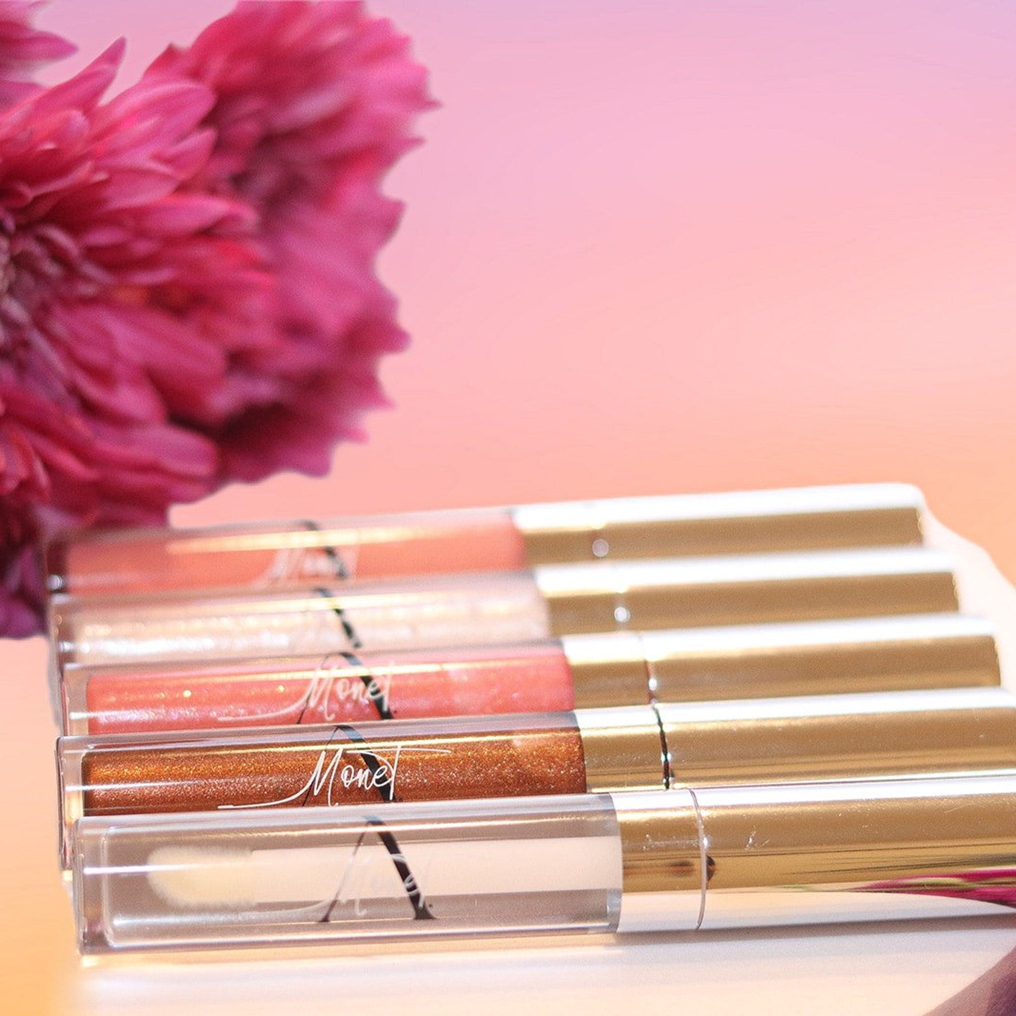 Lip gloss tubes with gold caps, clear tubes, and "Mone" text visible