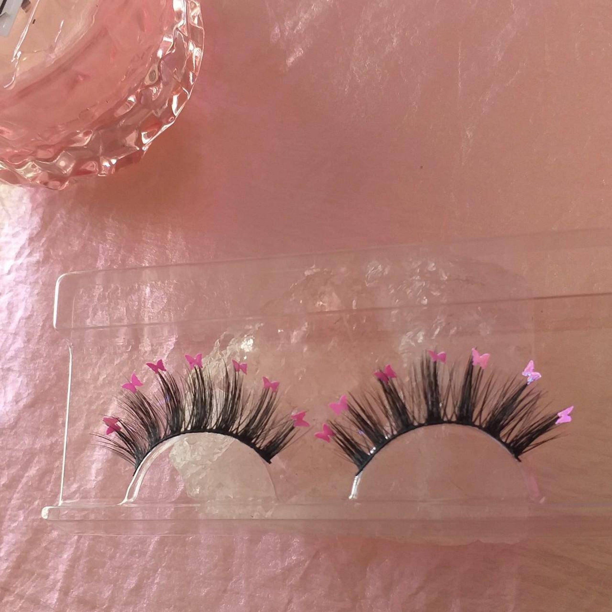 False eyelashes with black lashes, pink butterfly accents, and clear packaging