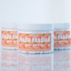 Body butter jars with white lids, peach labels, and Soogs Body Care branding