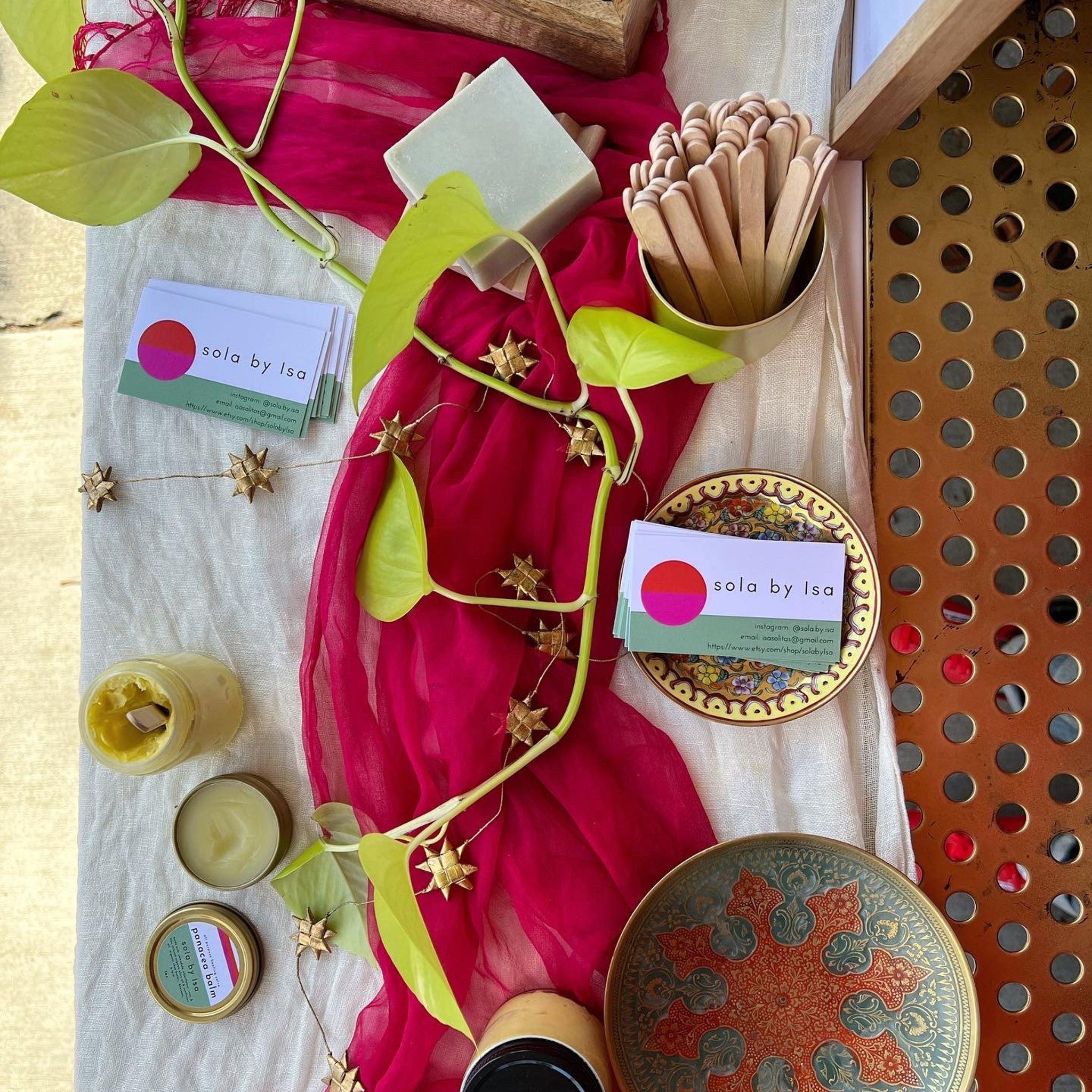 Business cards with sola by Isa branding, red and white background, gold star garland, and decorative plates