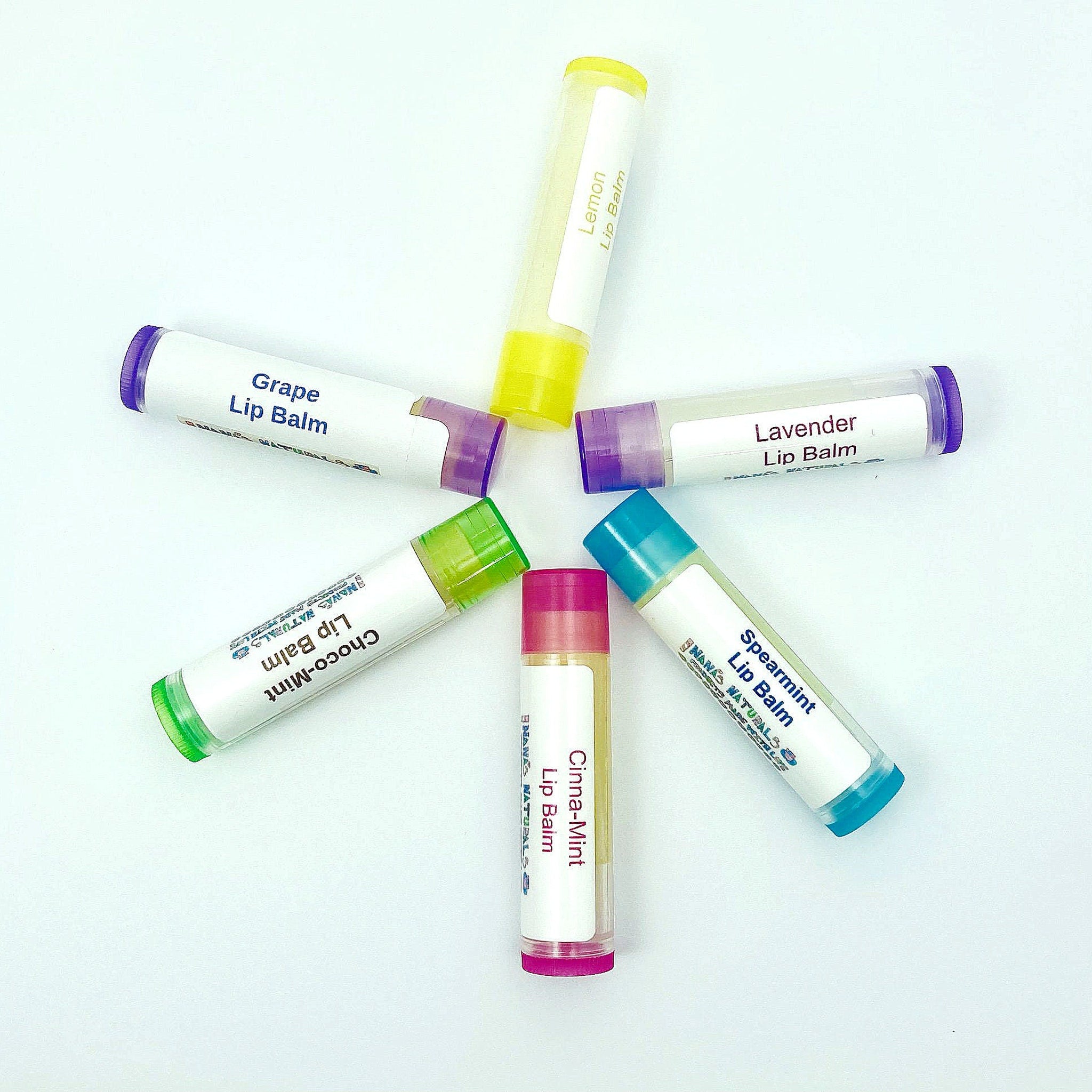 Lip balm tubes in various colors with labels, arranged in a circle, Nanas Naturals brand visible