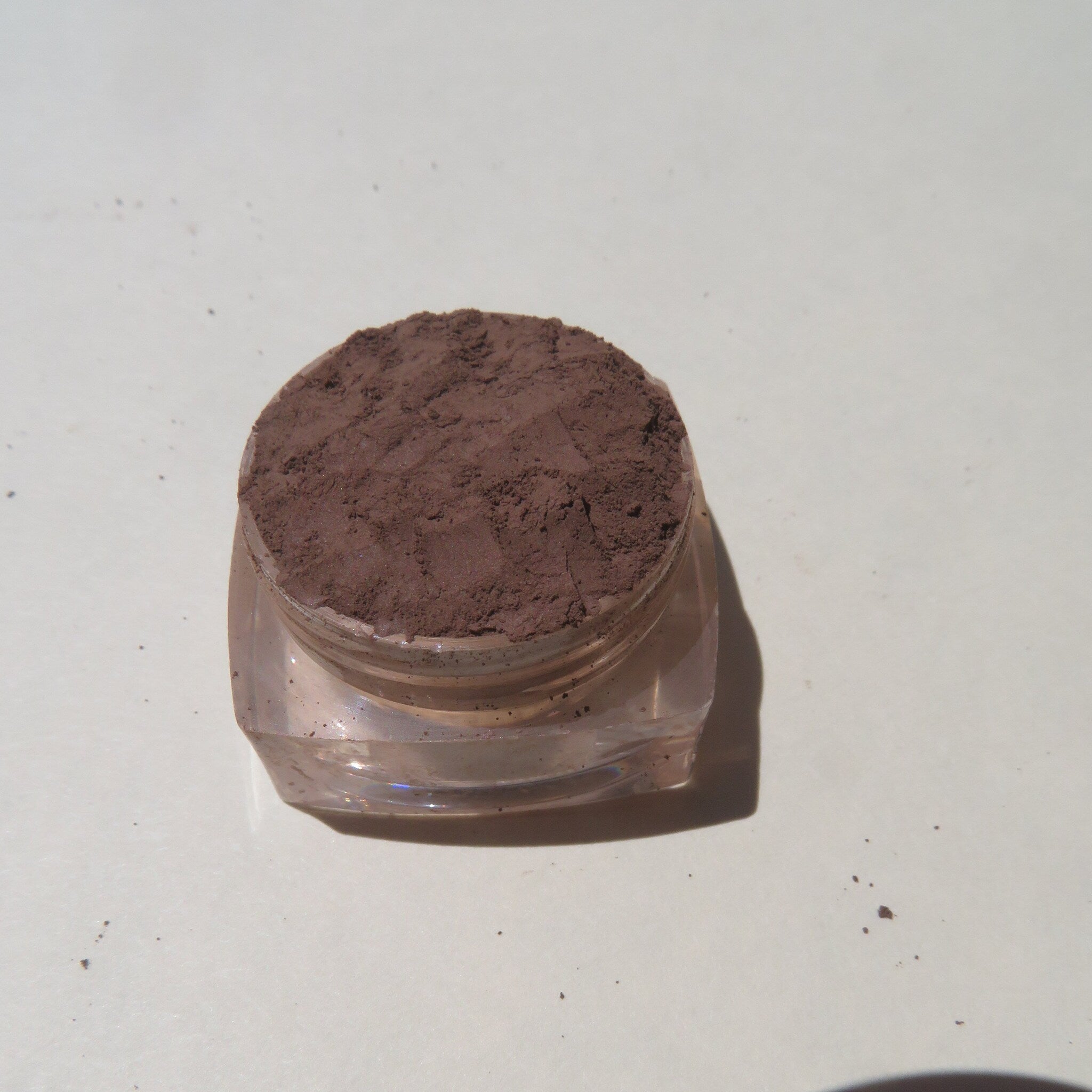Close-up of matte dark brown loose mineral eyeshadow powder with rich pigmentation in a vegan formula