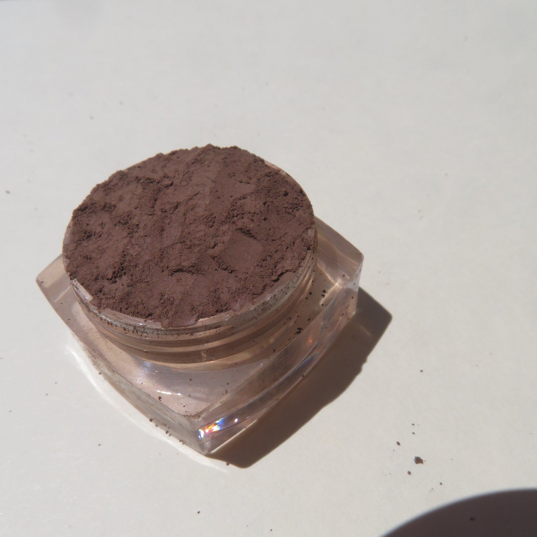 Dark brown matte mineral eyeshadow in a small black jar with silver lid and product label