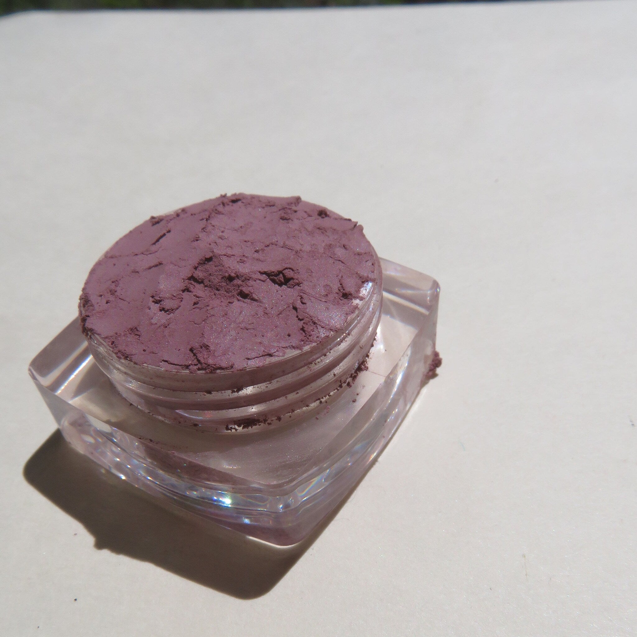 Close-up of matte purple loose mineral eyeshadow powder with fine texture in a small jar